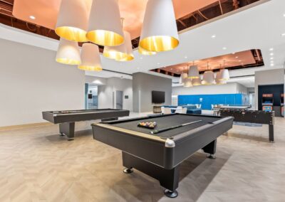 View of pool tables and lounge seating located inside the Amenity Hub with 24-hour package lockers in back.