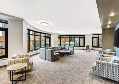 View of a social lounge with comfy seating, large TV, and panoramic view of the city.